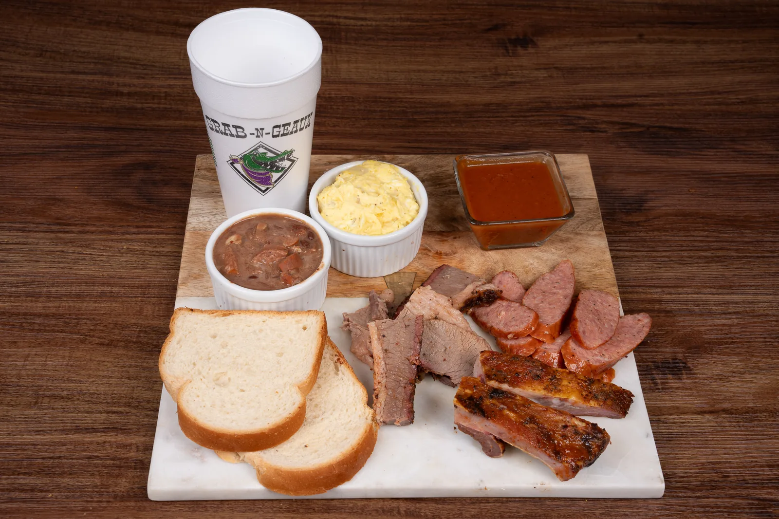 A plate of smoked brisket, sausage and ribs with sides